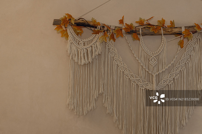 秋天的树叶挂在钩针编织的墙饰上。图片素材