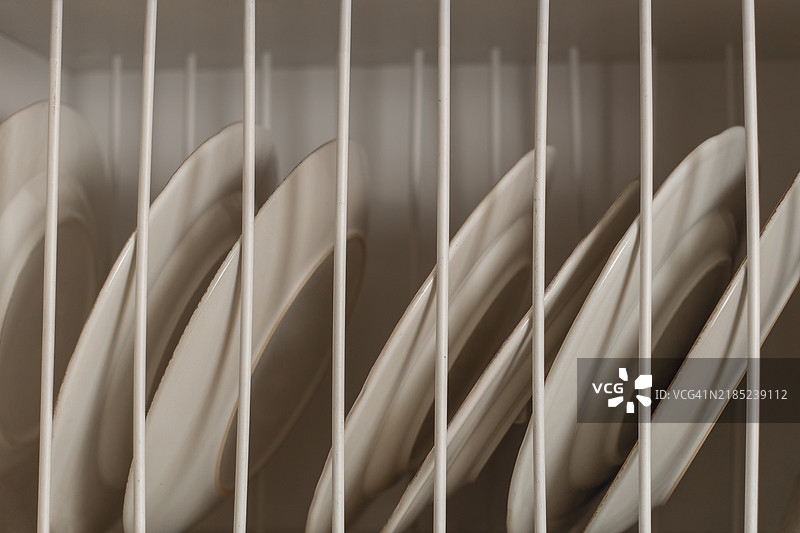 洗碗机架子上堆叠的盘子。图片素材