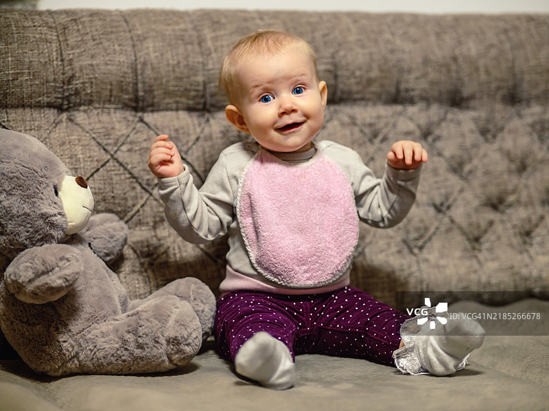 可爱的婴儿女孩坐在沙发上看着镜头图片素材