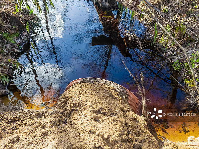 树林溪流中通过涵洞的变色水流图片素材