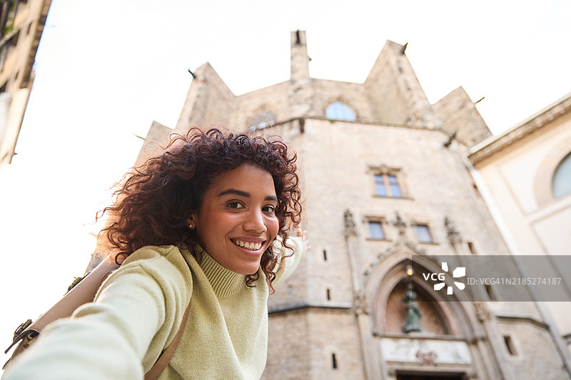 年轻女性网红在巴塞罗那圣玛丽亚德尔马大教堂前拍摄视频日志图片素材