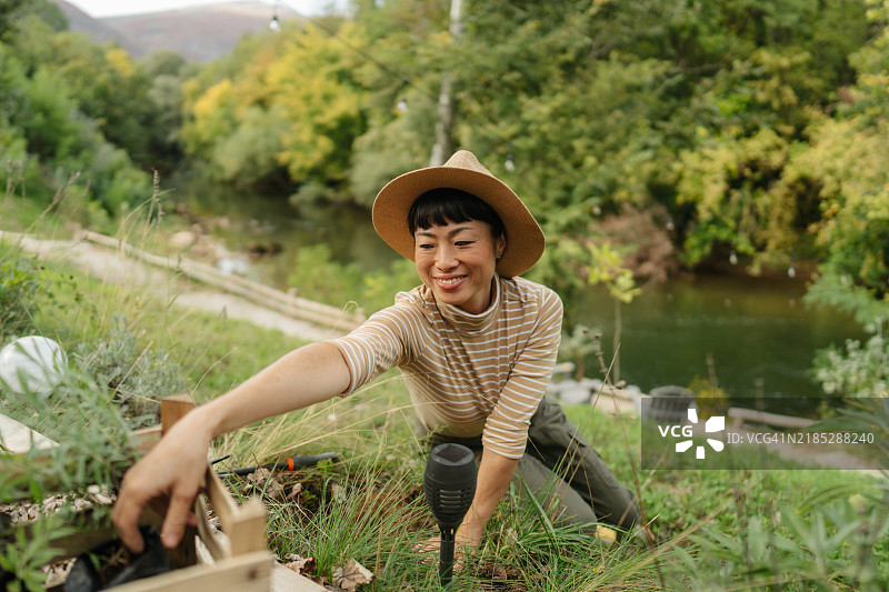 微笑的女性在风景如画的河边园艺图片素材