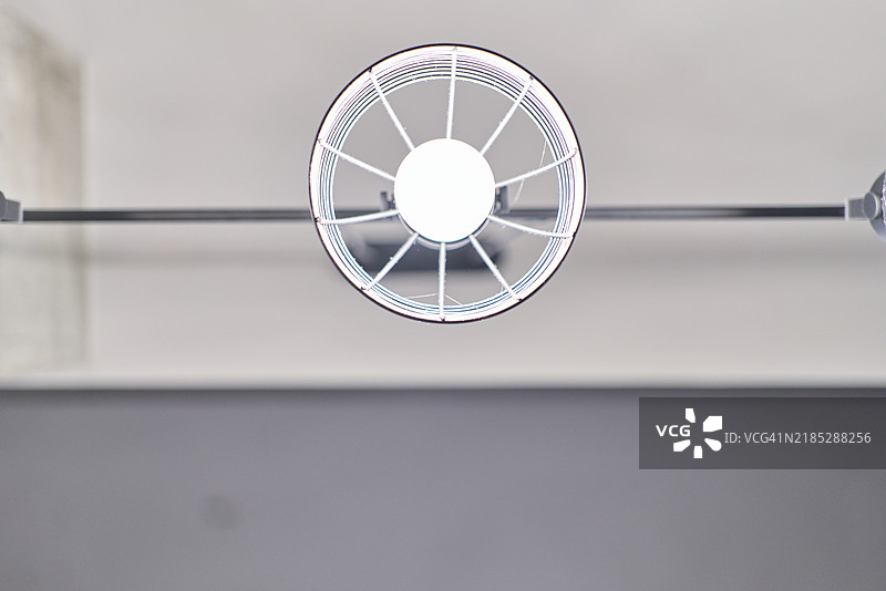 从低角度看，一个圆形灯具上亮着白色灯泡。图片素材