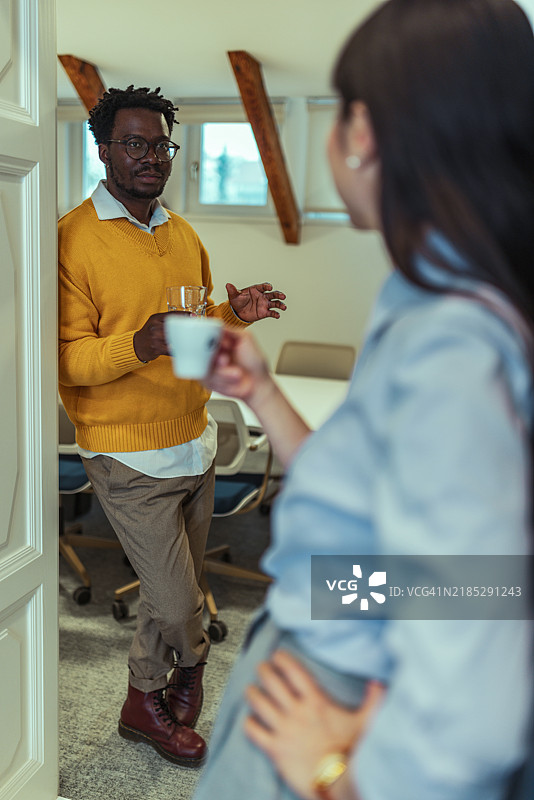 日本女商人与同事在办公室门口喝咖啡交谈图片素材