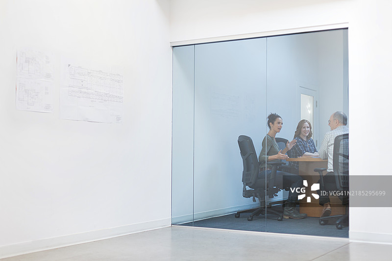 成熟的女性在办公室会议室中带领一组同事进行讨论。图片素材