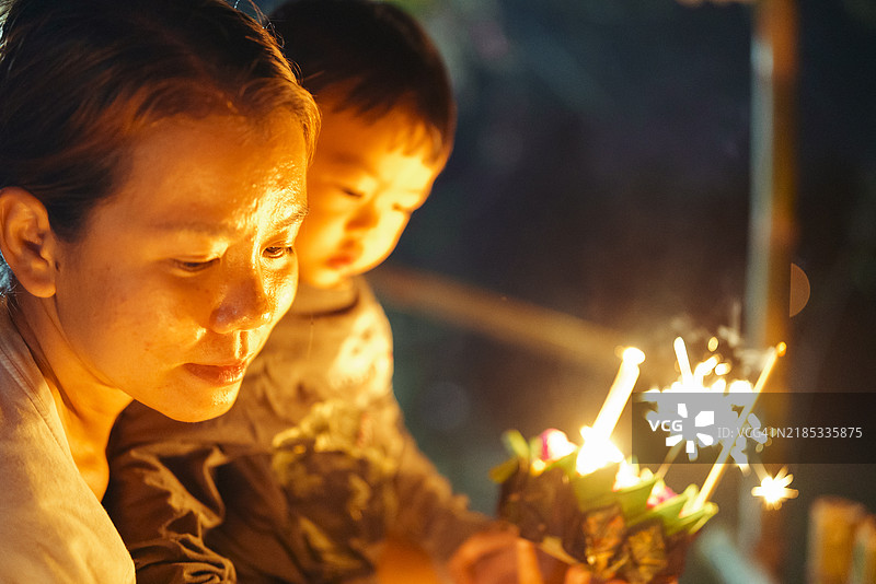 积极情绪的亚洲小女孩在家中享受水灯节的漂浮水灯，水灯节是一个向河流和恒河女神祈祷和表达敬意的传统节日。图片素材