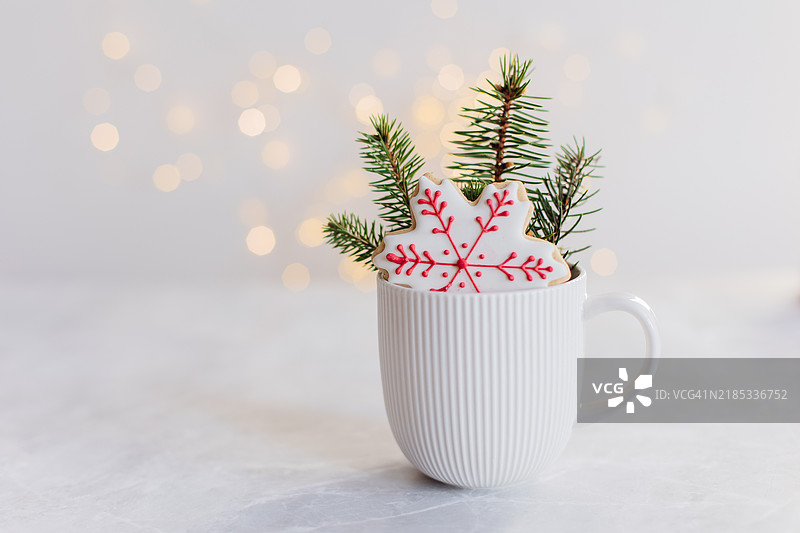 圣诞贺卡。白色陶瓷杯旁边放着松树枝，姜饼饼干呈雪花形状。留白空间。图片素材