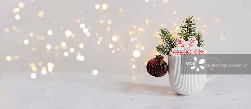 圣诞贺卡，配有杯子、松树枝、雪花形状的姜饼饼干和北欧风格的纸质蜂窝装饰。设计和网页的横幅图像，留白空间。图片素材