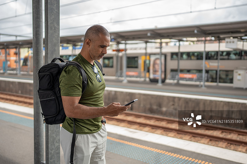 在火车站台上使用智能手机的男子图片素材