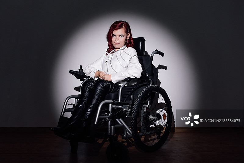 自信的轮椅女性在戏剧性的聚光灯下摆姿势图片素材