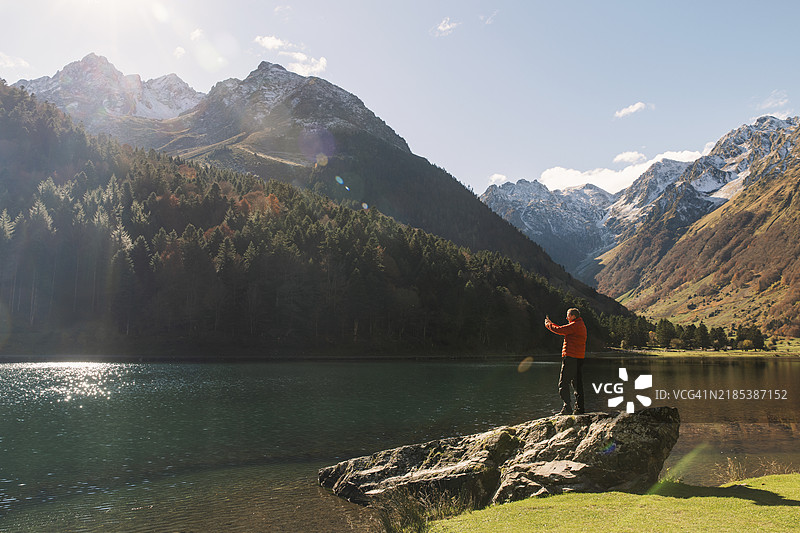 一位成熟男性在法国比利牛斯的热门旅游胜地埃斯坦湖拍摄美丽的秋季风景，镜头为广角。图片素材