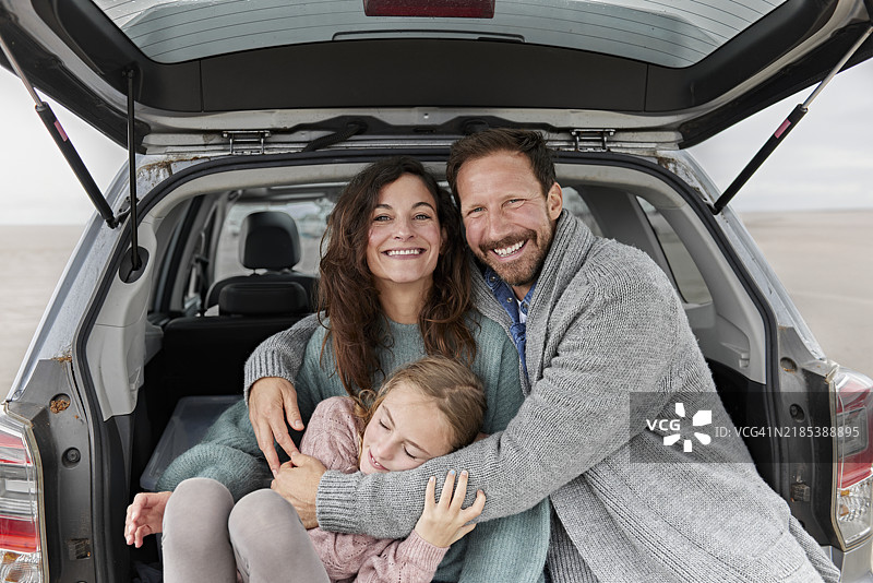 亲密的家庭坐在海滩上的汽车后备厢里图片素材