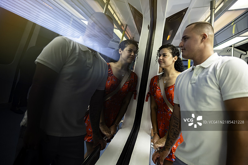 年轻的拉丁裔情侣乘坐公共交通地铁或轻轨图片素材