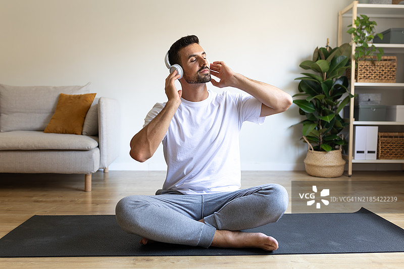 年轻男子在家中戴着耳机放松听音乐图片素材