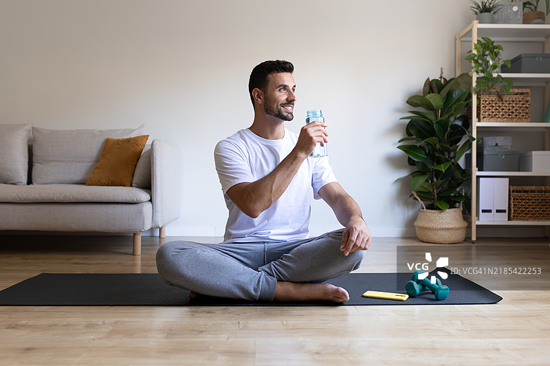 年轻男子在家健身后喝水图片素材