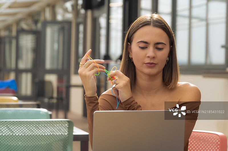 年轻女性在工作中使用电脑，借助橡皮筋、玩具和辅助设备来提高专注力。图片素材