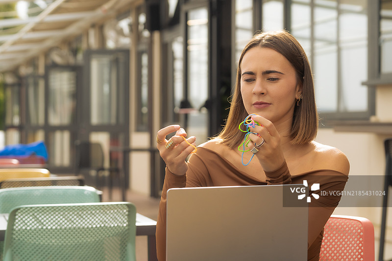 年轻女性在工作中使用电脑，借助橡皮筋、玩具和辅助设备来提高专注力。图片素材