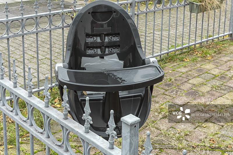 黑色塑料儿童自行车座椅固定在钢铁围栏上图片素材