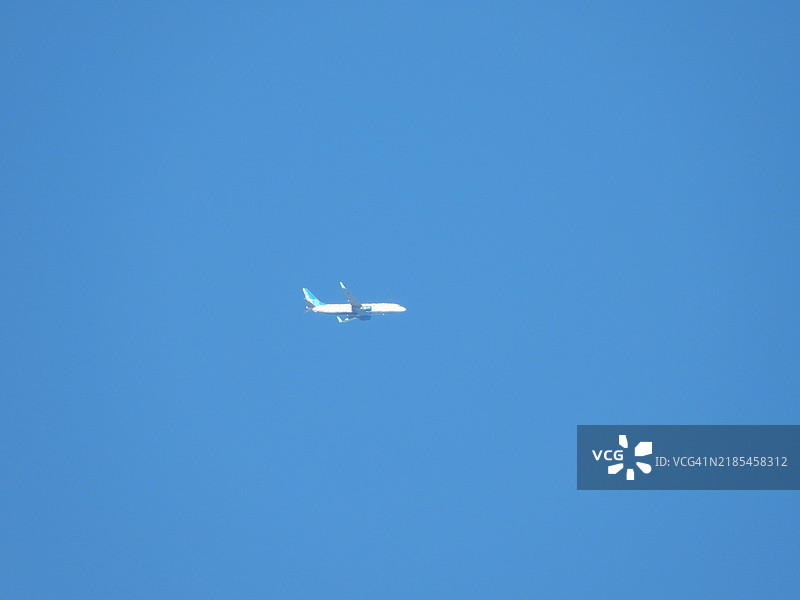 低角度视图的飞机在晴朗的蓝天中飞行图片素材