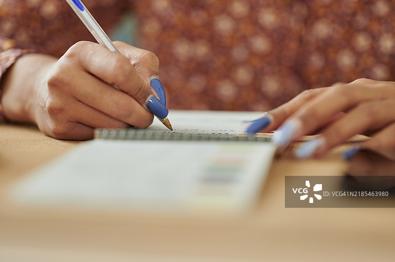 女人的手在笔记本上用笔写字的特写镜头图片素材