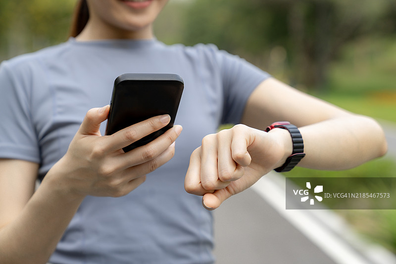女性在锻炼前将智能手表和智能手机配对图片素材
