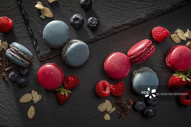 蓝莓和覆盆子马卡龙饼干，甜点放在黑色石板背景上图片素材