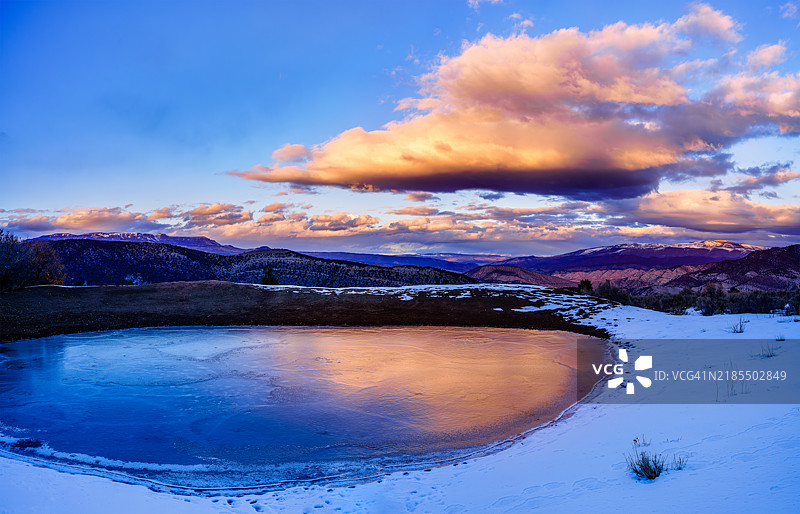 山脉日落风景与冰冻池塘中的倒影图片素材