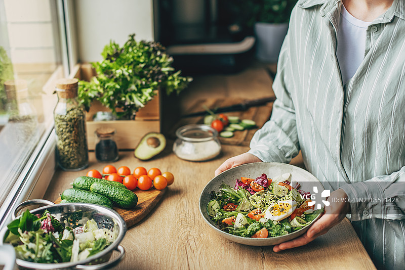 女人在厨房用木勺搅拌美味的超级食品沙拉配料图片素材