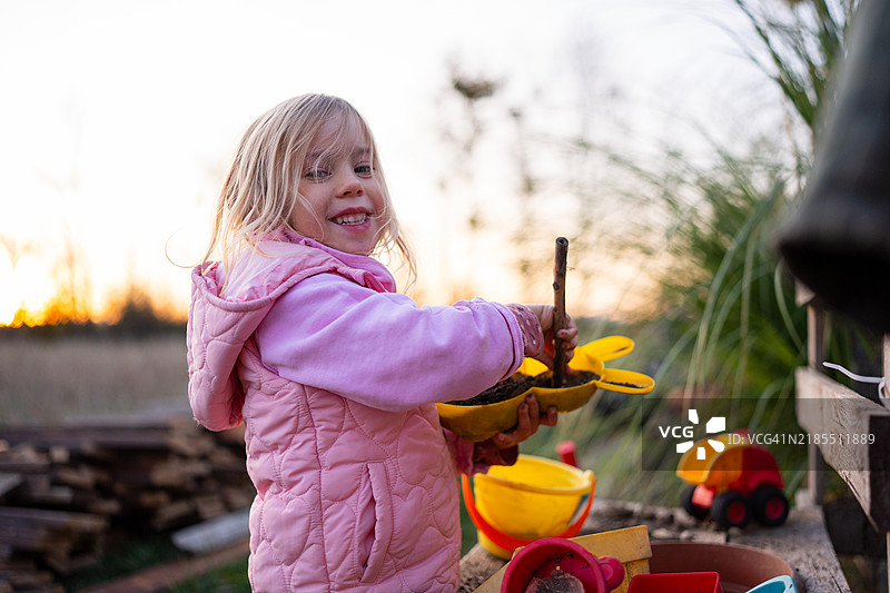 年轻女孩在乡村风景中的户外厨房玩耍图片素材