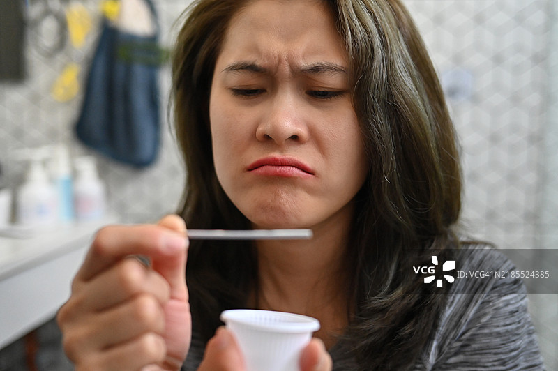 不快乐的女性使用LH排卵测试条的特写镜头。测试条提供准确清晰的怀孕可能性结果。图片素材