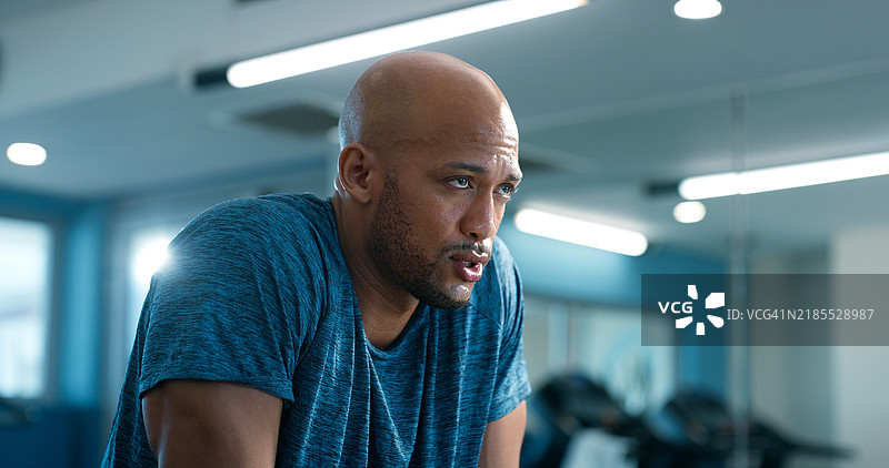 流汗的非洲男子在健身房中感到疲惫，专注于健康俱乐部的健身和运动。运动员在锻炼中喘息，休息片刻，进行力量训练，经历疲劳、恢复和耐力的挑战。图片素材