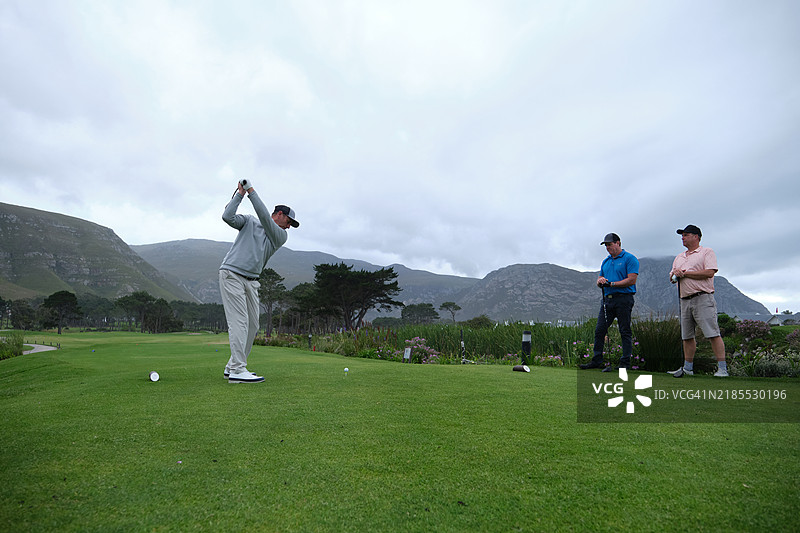 高尔夫球手在郁郁葱葱的球场上挥动高尔夫球杆图片素材