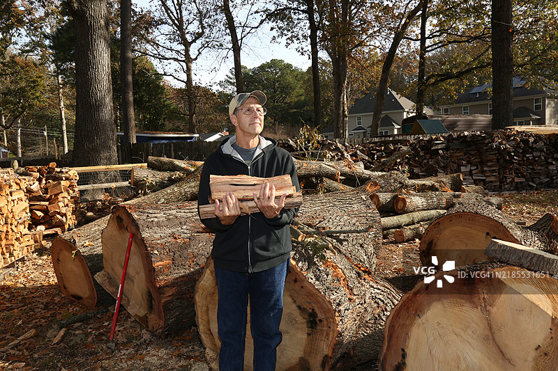 一个男人站在木柴堆旁边图片素材