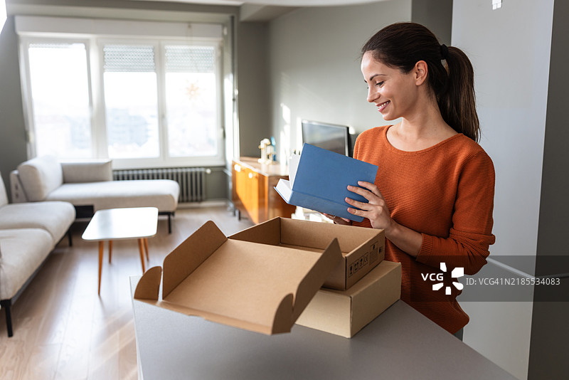 在线购物的乐趣：女人打开她的快递图片素材