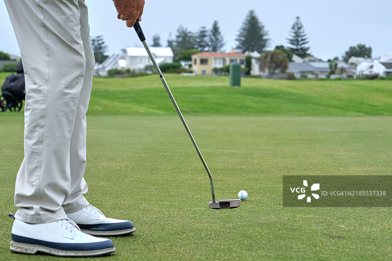 高尔夫球手在果岭上准备推杆的特写镜头图片素材
