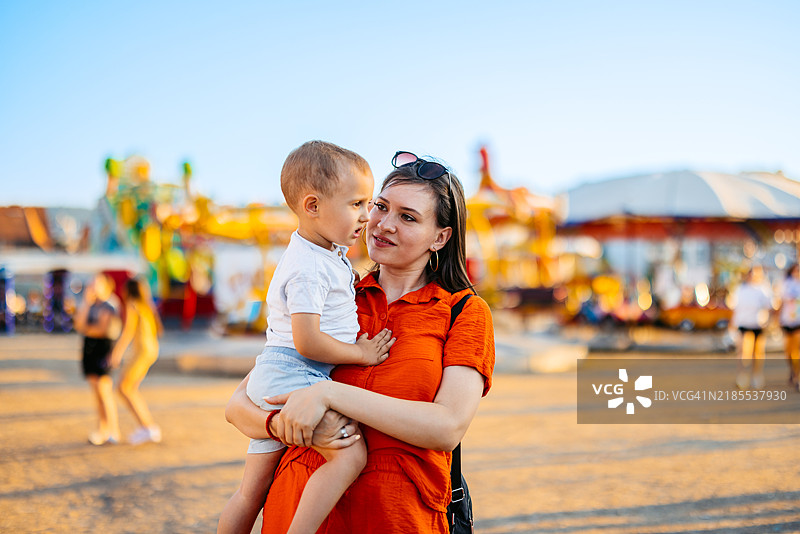 年轻母亲在游乐园抱着她的儿子图片素材
