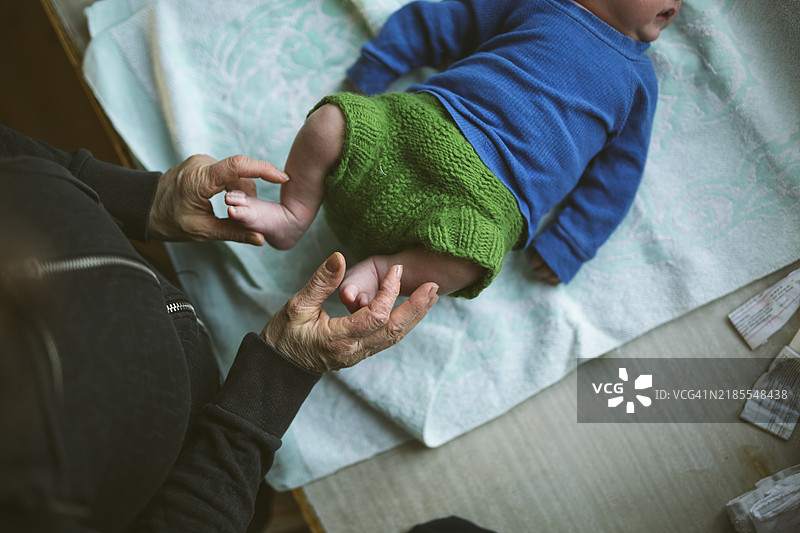老年女性抱着躺着的新生儿的脚图片素材