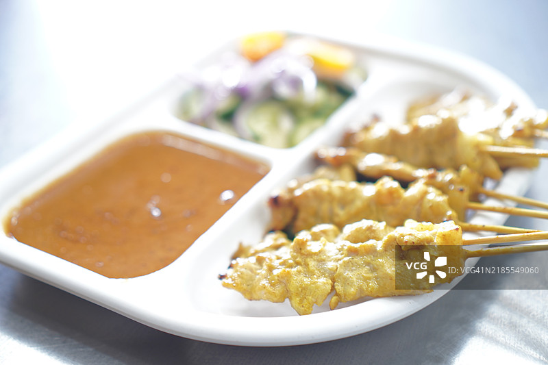 黄香料腌制的沙爹猪肉，穿在串上，烤至熟透，搭配酱汁和沙拉一起食用。图片素材