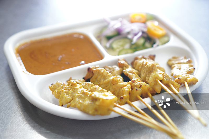 黄香料腌制的沙爹猪肉，穿在串上，烤至熟透，搭配酱汁和沙拉一起食用。图片素材