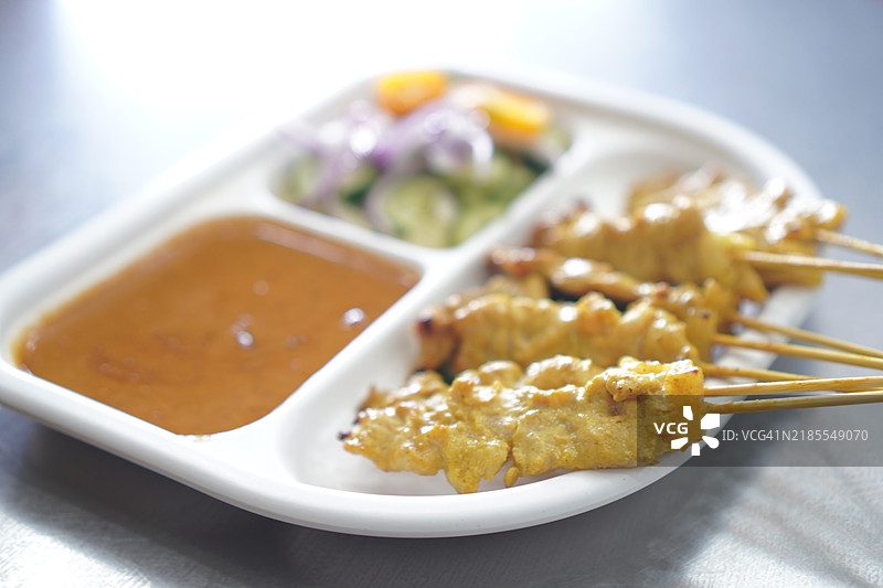 黄香料腌制的沙爹猪肉，穿在串上，烤至熟透，搭配酱汁和沙拉一起食用。图片素材