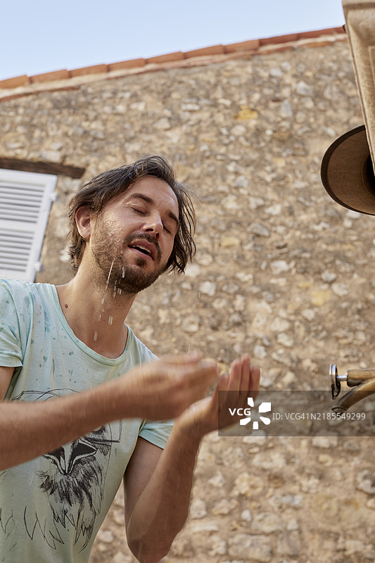 低角度视图的中年男子用水洗脸图片素材