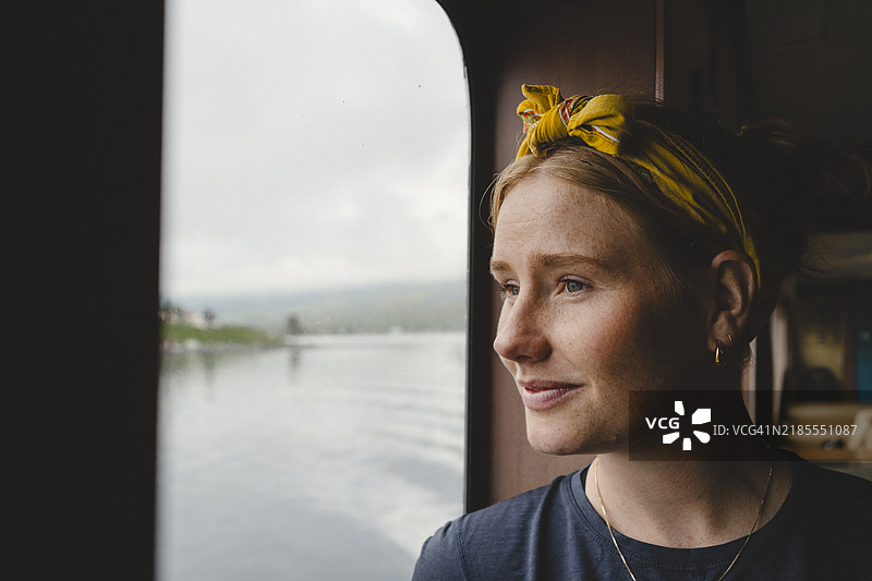在渡轮上透过窗户凝视的沉思女性特写镜头图片素材
