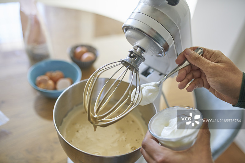 男子将酸奶加入自制蛋糕面糊中图片素材