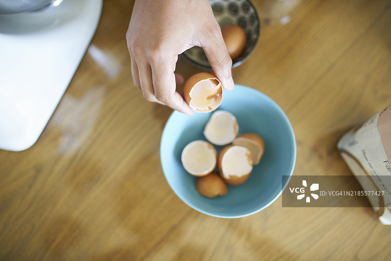 男人在家制作蛋糕，并将蛋壳放入碗中图片素材