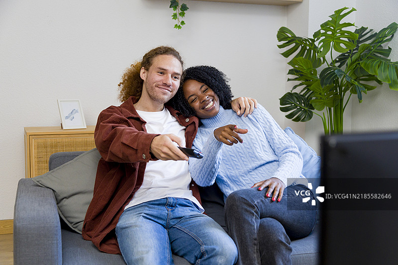 幸福的情侣在家沙发上拥抱着看电视图片素材