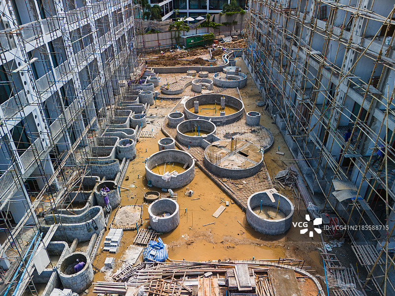 泥泞的建筑工地航拍照片，圆形混凝土基础、脚手架和散落的建筑材料。图片素材