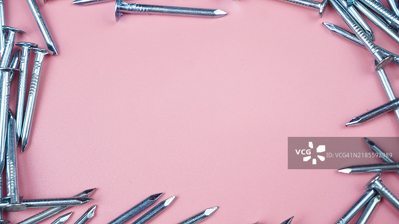 一堆钢钉围绕着空白的粉色背景图片素材