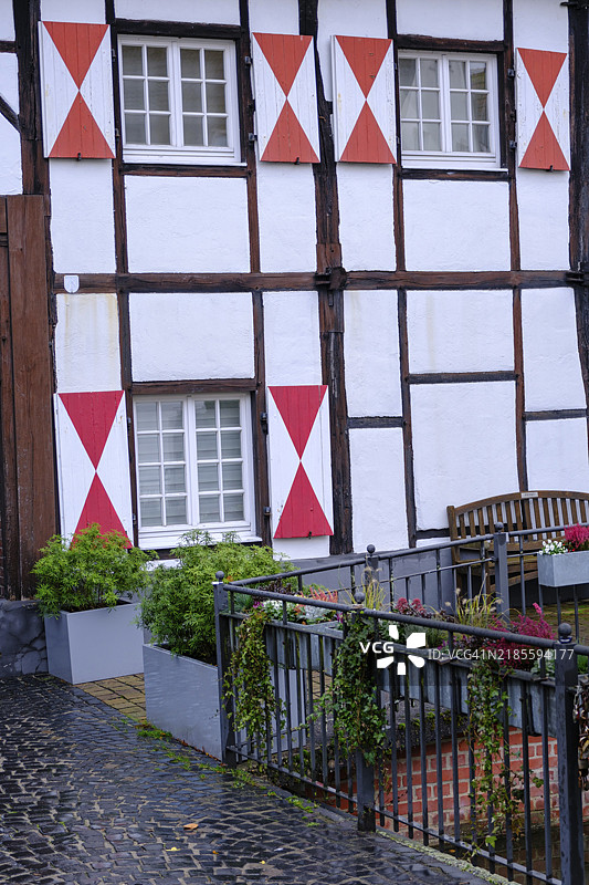 城市小巷中带有红色图案和花卉装饰的半木结构房屋细节，德国明斯特地区的盖门。图片素材