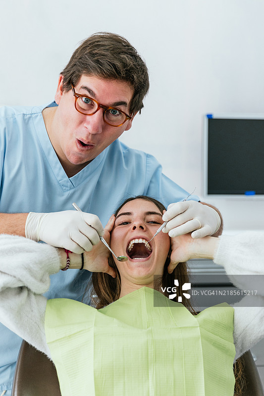 牙医正在给一位害怕的年轻女性进行牙齿检查图片素材
