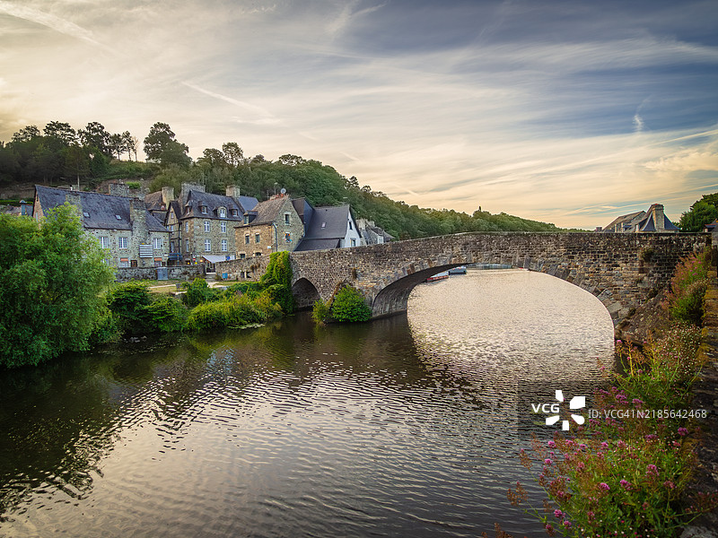 日落时分的迪南老桥（Vieux Pont）景观，这是一座被列为历史遗迹的石拱桥，背景是拉朗斯河以及下层中世纪城镇的码头和滨水区，位于法国西部的布列塔尼（Bretagne）科特迪瓦尔省（Cotes-d'Armor）。图片素材